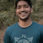 Portrait of a cheerful young man standing outdoors with natural background.
